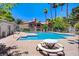 Community pool surrounded by lounge chairs, picnic tables, and tall palm trees at 220 Mission Newport Ln # 105, Las Vegas, NV 89107