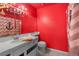 Vibrant red bathroom featuring a white sink, toilet, and an anchor-themed shower curtain at 2500 Cortina Ave, Henderson, NV 89074