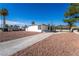Single-story home featuring a gravel front yard, long driveway, and covered carport against a clear, blue sky at 2878 El Cajon St, Las Vegas, NV 89169