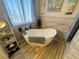 A freestanding white bathtub with modern black fixtures sits next to a window with sheer blue curtains at 3031 Pebble Beach Ave, Pahrump, NV 89048