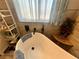 Close-up view of a white bathtub with black fixtures and sheer curtains, surrounded by decorative shelves at 3031 Pebble Beach Ave, Pahrump, NV 89048