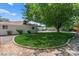 Well-maintained backyard with a lush lawn, mature tree providing shade, and a concrete border for landscaping at 3108 Sonia Dr, Las Vegas, NV 89107