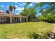 Expansive green backyard featuring a covered patio area with decorative pillars, lush greenery, and palm trees at 4530 W Shelbourne Ave, Las Vegas, NV 89139
