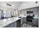 Modern kitchen featuring gray cabinetry, stainless steel appliances, and a breakfast bar overlooking the living area at 7241 Indian Creek Ln # 203, Las Vegas, NV 89149