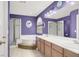 Stylish purple-toned bathroom with double sinks, a separate shower, and a large soaking tub at 7437 Treasure Chest St, Las Vegas, NV 89139