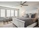 Bright bedroom featuring a large bed, stylish seating, plantation shutters, and ceiling fan at 8175 Caldera Creek St, Las Vegas, NV 89113