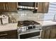 Close up of gas range, stainless steel microwave, and light gray subway tile backsplash at 8175 Caldera Creek St, Las Vegas, NV 89113