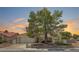 Inviting single-story home boasts mature landscaping, a tile roof, and a cozy front porch at sunset at 8813 Sundial Dr, Las Vegas, NV 89134