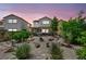 Twilight view of home's backyard featuring desert landscaping, rock features, shrubbery, and inviting patio at 10312 Glimmering Star Dr, Las Vegas, NV 89178