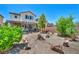Home's backyard featuring desert landscaping, rock features, shrubbery, and inviting covered patio at 10312 Glimmering Star Dr, Las Vegas, NV 89178