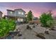 Twilight view of home's backyard featuring desert landscaping, rock features, shrubbery, and inviting patio at 10312 Glimmering Star Dr, Las Vegas, NV 89178