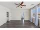 Spacious bedroom with an en-suite bath, ceiling fan, wood-look floors and windows with curtains at 11484 Roncat Ct, Las Vegas, NV 89141