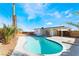Large pool in the backyard with a desert landscape, palm trees, privacy fence, and a covered patio at 2 Utah Way, Henderson, NV 89015