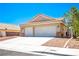 Two-car garage with a concrete driveway, desert landscaping, and tile roof detail at 218 Red Coral Dr, Henderson, NV 89002