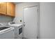 Functional laundry room with white appliances, wood cabinets, and a door to the exterior of the home at 218 Red Coral Dr, Henderson, NV 89002