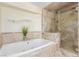 Luxurious bathroom with a soaking tub and glass-enclosed shower with travertine tile at 3085 Duneville St, Las Vegas, NV 89146