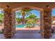 Stone archway framing tropical pool area with cabana and 'Welcome to Paradise' sign at 3085 Duneville St, Las Vegas, NV 89146