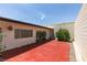 Enclosed backyard featuring a red concrete patio, exterior string lights, and lush potted plants at 3785 Decade St, Las Vegas, NV 89121