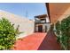 Multi-level backyard featuring a red patio, block walls, and a charming balcony above at 3785 Decade St, Las Vegas, NV 89121