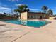 A community pool with clear, turquoise water, surrounded by a concrete deck and lush palm trees and cityscape in the background at 3911 Torsby Pl, Las Vegas, NV 89119