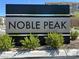 Landscaped view of the community sign for Noble Peak with black and silver color scheme at 4533 Queens Hill St, North Las Vegas, NV 89031