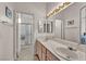 Well-lit bathroom featuring a large mirror, dual sink vanity, and a glass-enclosed shower at 5139 Zapata Ln, North Las Vegas, NV 89031