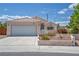 Single-story home with a tile roof, desert landscaping, and a large driveway leading to a two-car garage at 5139 Zapata Ln, North Las Vegas, NV 89031