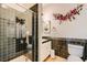Modern bathroom with sleek black tiles, a glass-enclosed shower, and stylish floral accents at 5409 Flora Spray St, Las Vegas, NV 89130