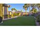 Backyard featuring an artificial lawn surrounded by lush landscaping, plants, and mature palm trees at 6120 Kings Brook Ct, Las Vegas, NV 89149