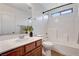 This bathroom features a tiled shower-tub and a wood vanity with white sink at 7704 Lots Hills Dr, Las Vegas, NV 89179