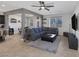 Open living room with gray sofa, dark ottoman, ceiling fan, and tile flooring at 7720 Houston Peak St, Las Vegas, NV 89166