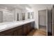 Bright bathroom with double sinks, marble countertops, dark wood cabinets, and a glass-enclosed shower at 8753 Mann St, Las Vegas, NV 89139