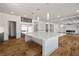 Open kitchen boasts a large island with granite counters, stainless steel fridge, and wood flooring at 8753 Mann St, Las Vegas, NV 89139