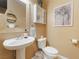 Tastefully decorated half bathroom with a pedestal sink, toilet, and decorative mirror, perfect for guests at 8808 Homestead Rd, Las Vegas, NV 89143