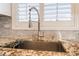 Close-up of a kitchen sink with granite countertops and stylish faucet, complemented by natural light from the window at 8808 Homestead Rd, Las Vegas, NV 89143
