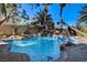 Tranquil backyard pool area with a rock waterfall, surrounded by palm trees and lush landscaping at 902 Cripple Creek Ct, Henderson, NV 89014