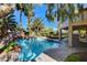Backyard oasis featuring a sparkling pool with rock features, palm trees, and a covered patio area at 902 Cripple Creek Ct, Henderson, NV 89014