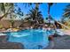 Beautiful backyard pool with rock waterfall, mature palm trees, and stamped concrete decking, creating a private oasis at 902 Cripple Creek Ct, Henderson, NV 89014