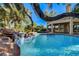 Inviting backyard pool with rock waterfall feature, lush palm trees, and covered patio, perfect for outdoor living at 902 Cripple Creek Ct, Henderson, NV 89014