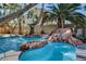 Backyard pool with a rock waterfall feature with flagstone coping and blue tile accents, surrounded by mature trees at 902 Cripple Creek Ct, Henderson, NV 89014