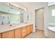 Bright bathroom with double sinks, wood cabinets, tile flooring, and separate tub and shower at 9122 Mountain Maple Ct, Las Vegas, NV 89148