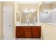 Bathroom featuring double sinks, a wood cabinet, and a window to the shower at 10463 Pioneer Park Ave, Las Vegas, NV 89135