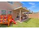 Spacious backyard with a covered patio, play structure, and lush green lawn for Gathering fun at 106 Rock Crossing Ave, North Las Vegas, NV 89031