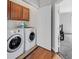 Well-equipped laundry room features side-by-side washer and dryer, wooden cabinetry and hardwood flooring at 10601 Lessona St, Las Vegas, NV 89141