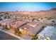 A dusk view of a home with desert landscaping with the city skyline in the distance at 12295 Skyracer Dr, Las Vegas, NV 89138
