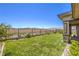 A lush green backyard with a wrought iron fence with beautiful views of the mountains beyond the landscaped yard at 12295 Skyracer Dr, Las Vegas, NV 89138