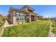 Exterior view of a modern home featuring a lush green lawn with manicured landscaping and a covered patio at 12295 Skyracer Dr, Las Vegas, NV 89138