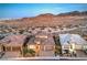 A well lit home displaying a three car garage with desert landscaping at dusk at 12295 Skyracer Dr, Las Vegas, NV 89138