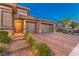 Attractive single-story home at dusk with a two-car garage, desert landscaping, and brick-paved driveway at 12295 Skyracer Dr, Las Vegas, NV 89138