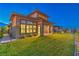 Exterior view of a modern home featuring a lush green lawn with manicured landscaping and a covered patio at dusk at 12295 Skyracer Dr, Las Vegas, NV 89138